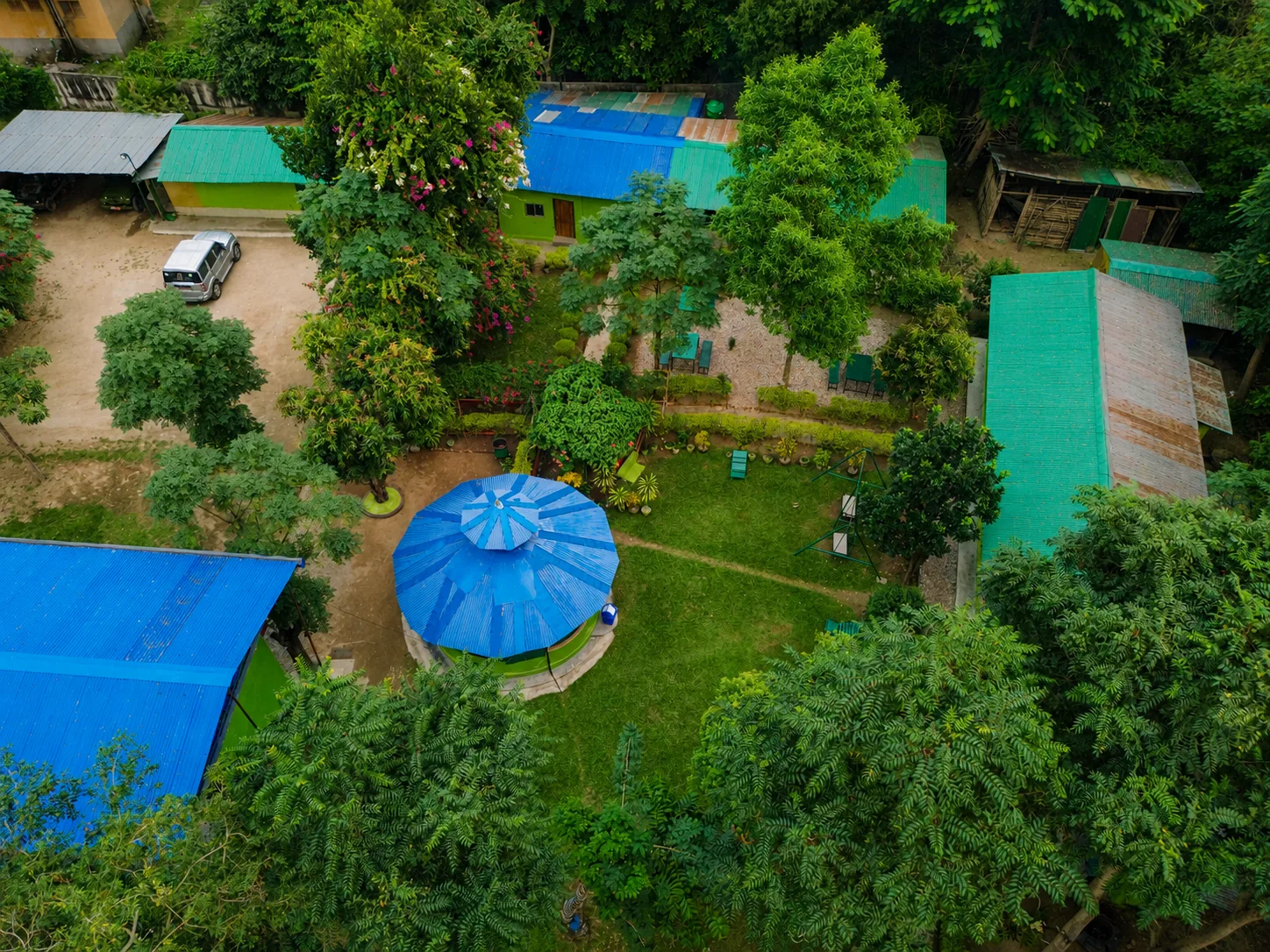 Drone view looking down over Shuklaphanta Jungle Cottage grounds, gardens and rooftops