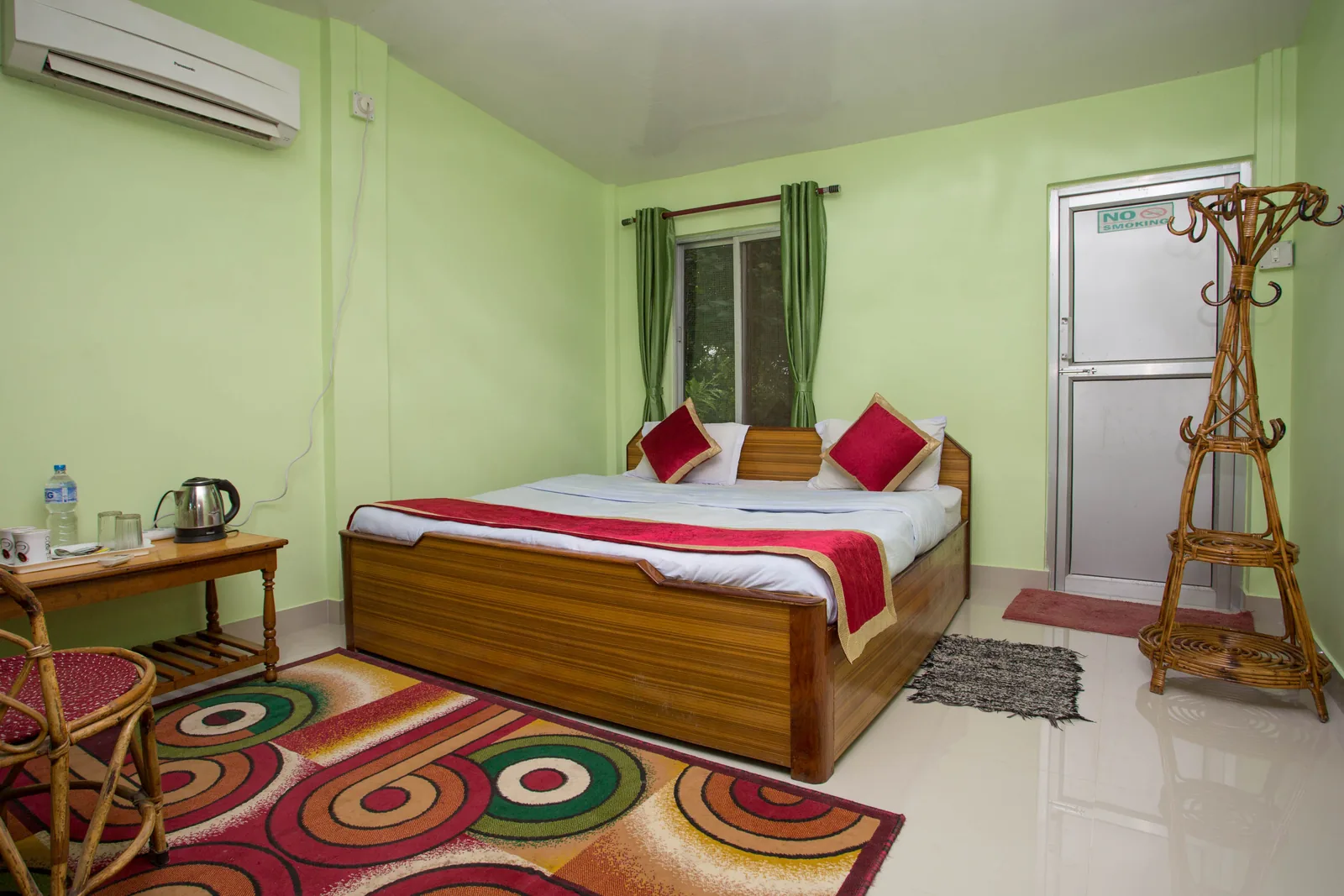 Master bedroom at Shuklaphanta Jungle Cottage — double bed, air conditioning and writing desk